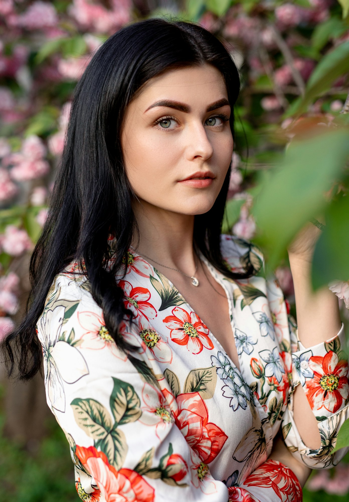 Graceful woman with perfect skin near flowering tree